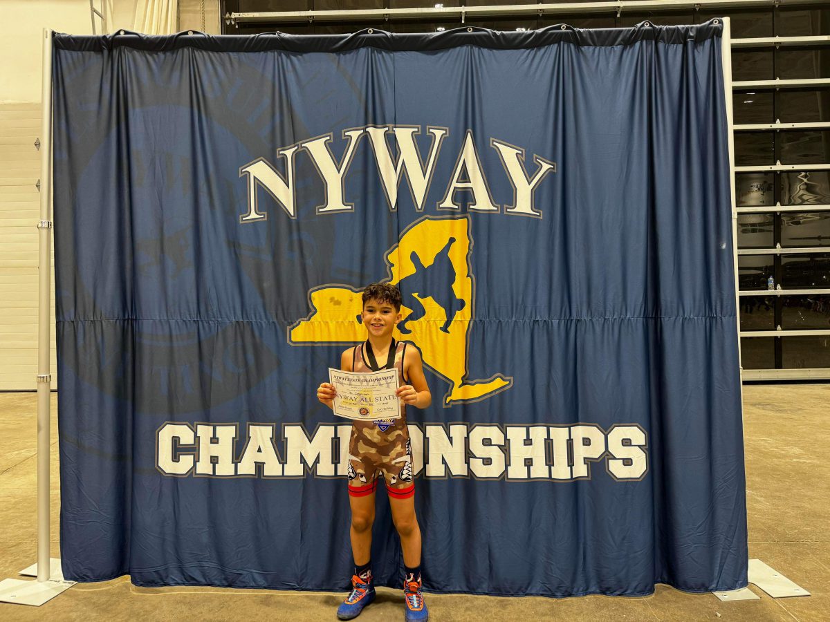 a student holds a certificate in front of a NYWAY Championship banner