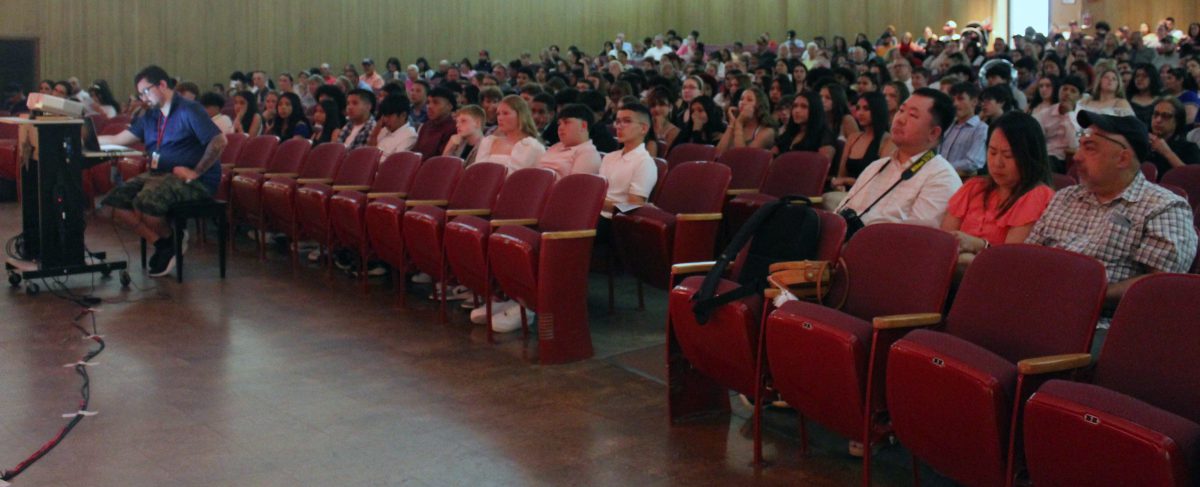Students and audience members watch speakers on stage