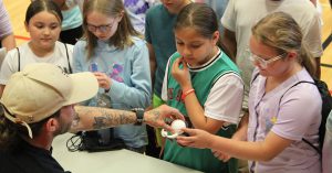 An adult gives students 3-d printed figures to look at 