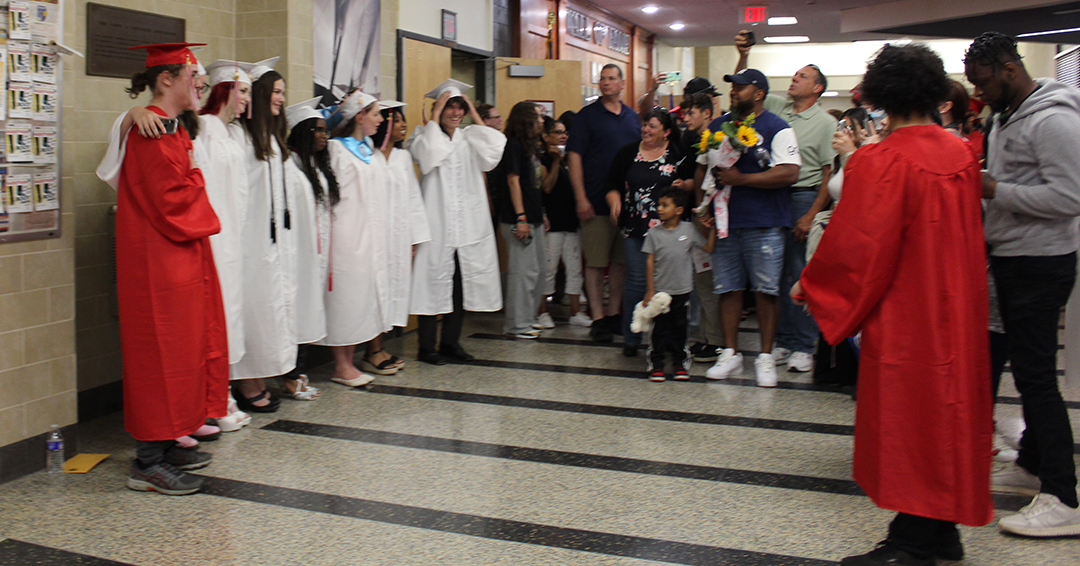 Seniors in caps and gowns pose as friends and families take pictures