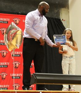 A teacher hands a certificate to a student