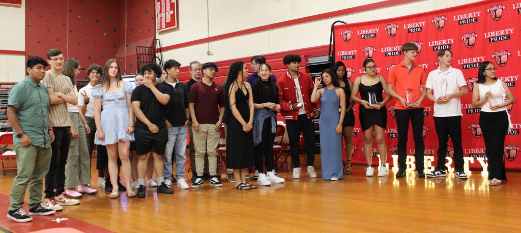 Seniors pose for a photo in front of a backdrop.