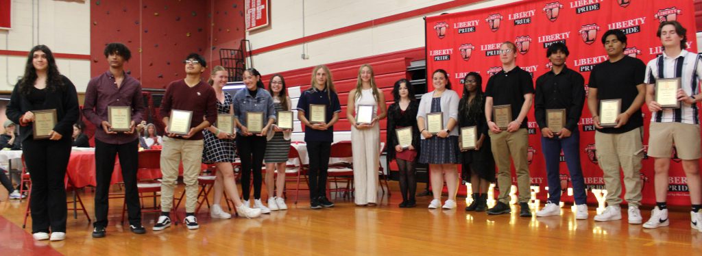 Students stand holding certificats.