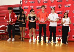 Six students pose with awards in front of the Liberty backdrop