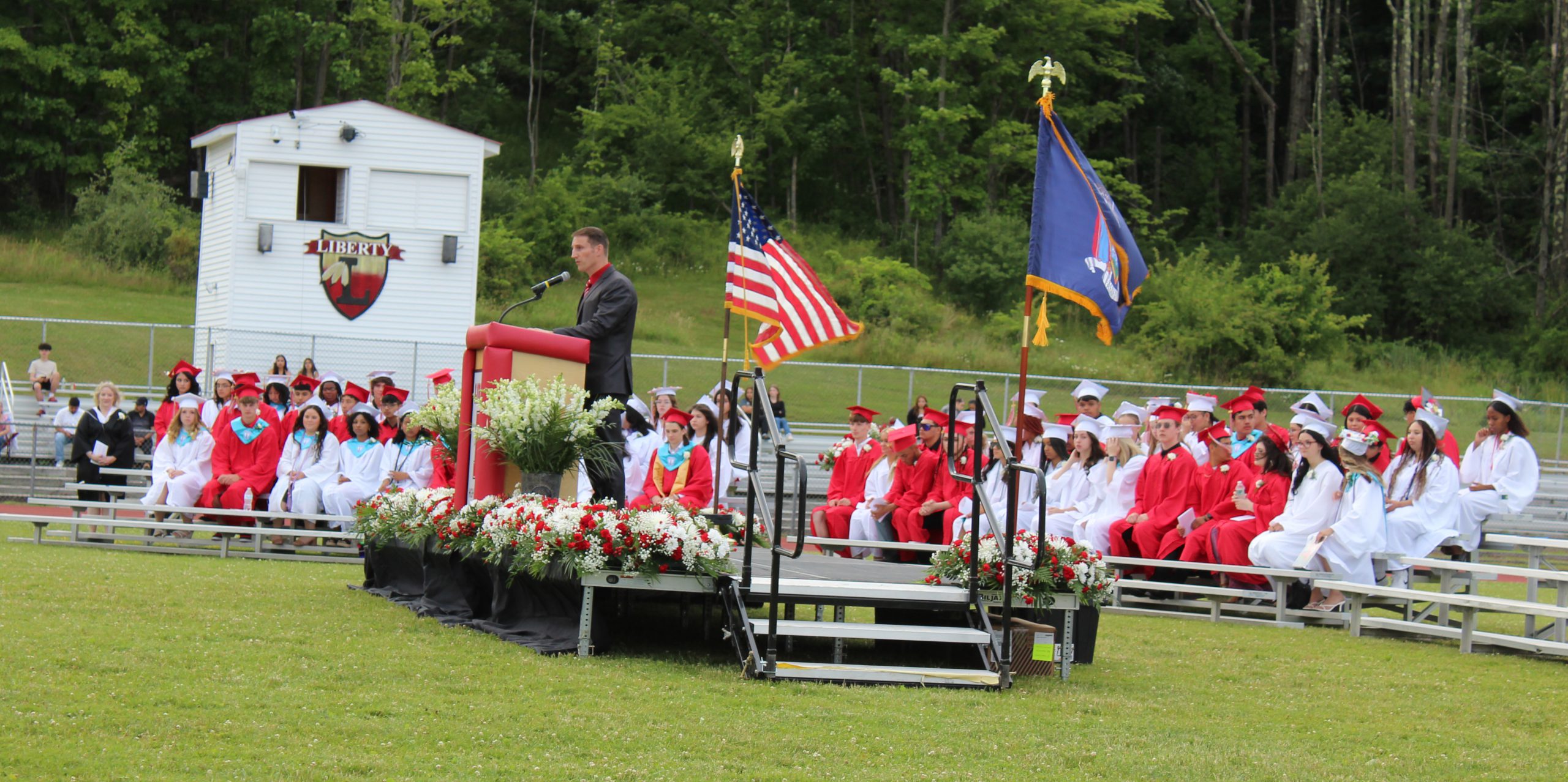 IMG_7520 A man speaks at a podium as graduates sit on bleachers