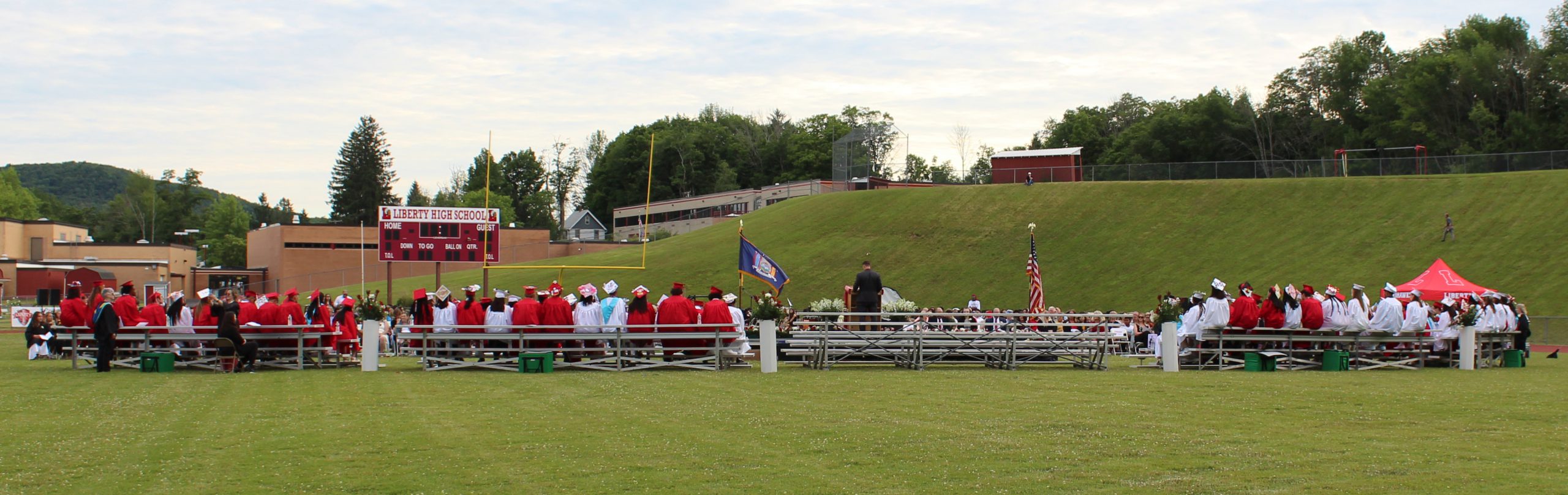 IMG_7523 Graduates sit on bleachers, as seen from the back.