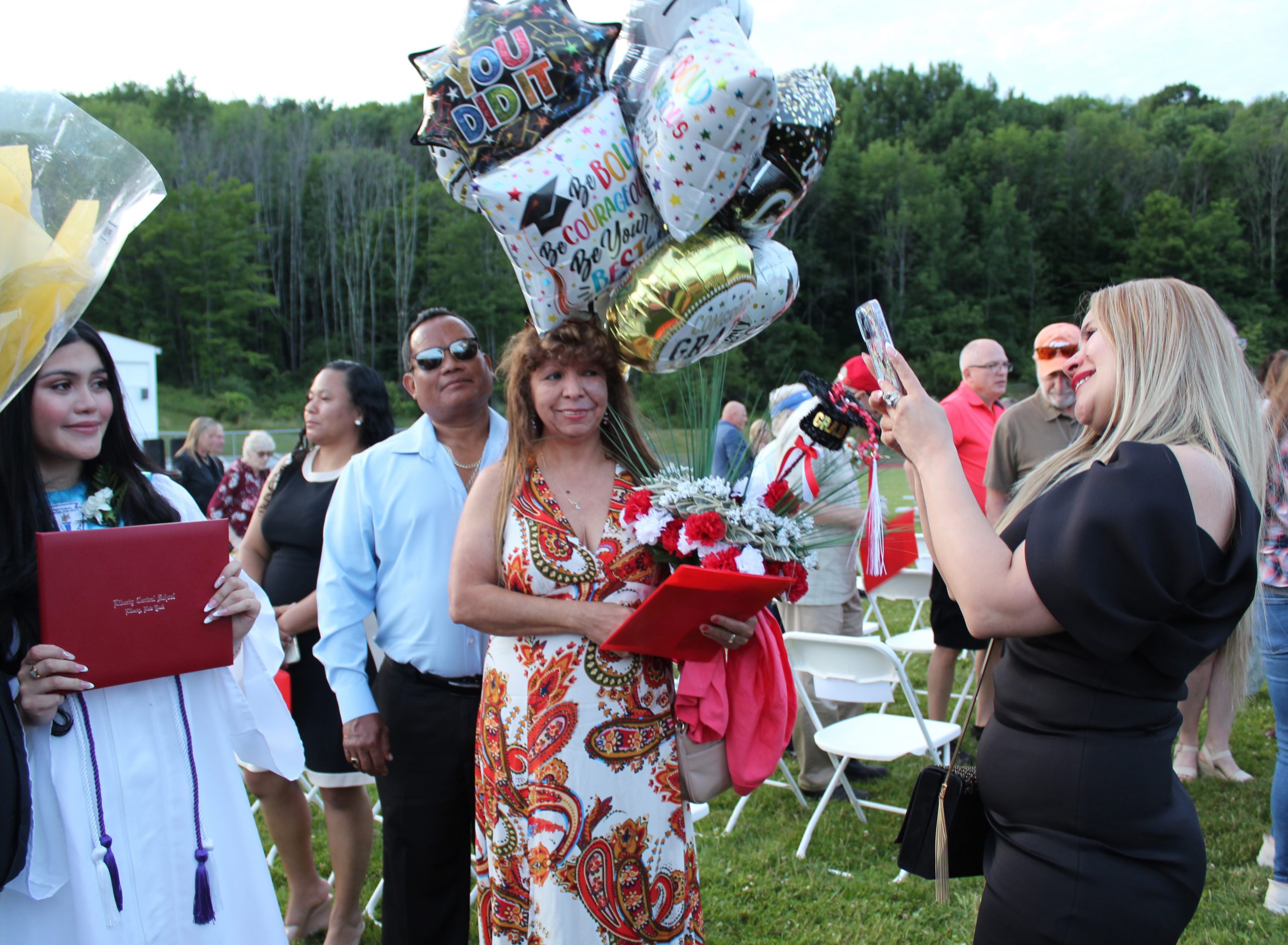 IMG_7724 An adult takes a photo of a graduate as another adult holds a bunch of balloons