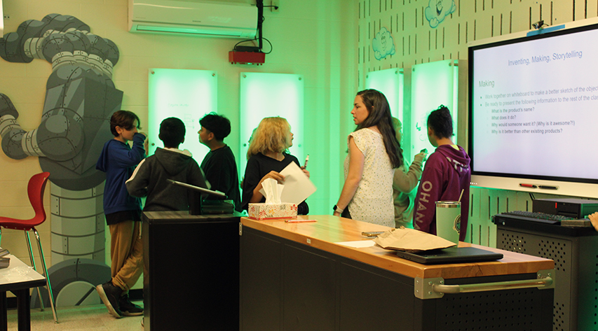 Students work at lighted whiteboards in the InventionLand innovation lab