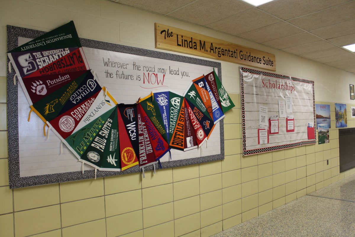 College banners are hung on a bulletin board with the words wherever the road may lead you the future is now., next to another bulletin board with Scholarships and folders with scholarship information over it. Above a wooden sign reads the Linda M. Argentati Guidance Suite