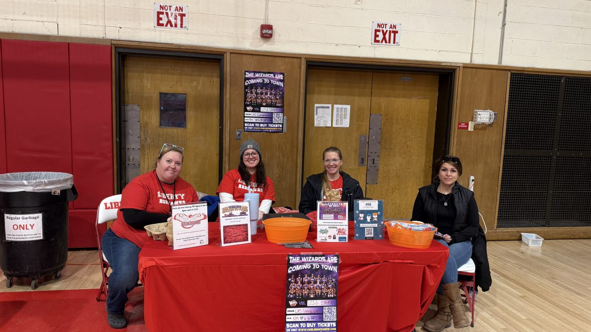 Four people sit at a table with posters