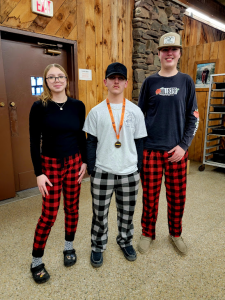 A student with a medal around his neck stands between two other students