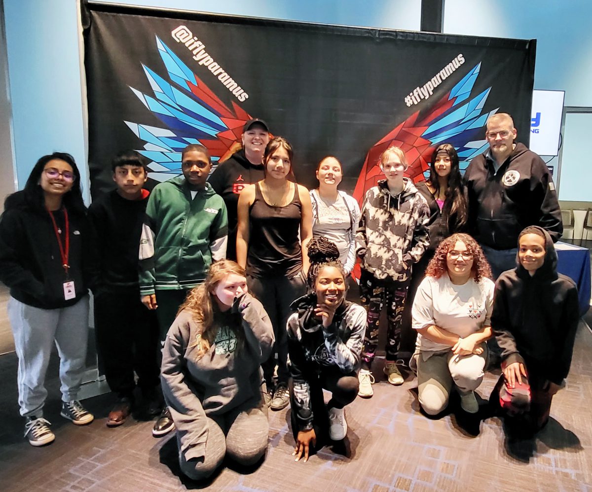A group poses in front of a backdrop with butterfly wings