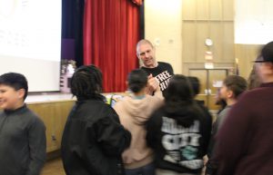 A man with a free hugs T-Shirt shakes a students hand in an auditorium