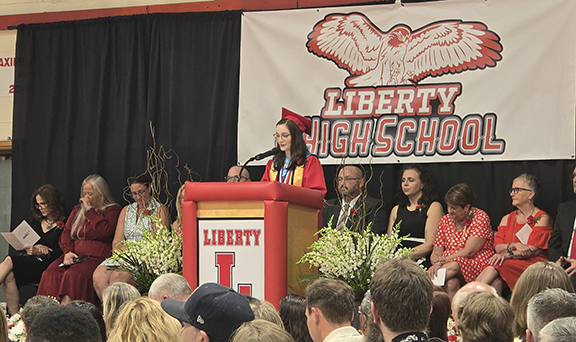 graduation35 A student speaks at a podium with board members and administrators behind them