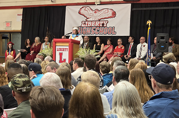 graduation34 A student speaks at a podium with board members and administrators behind them