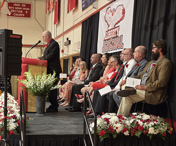 graduation32 A man speaks on a stage with board members and administrators behind him