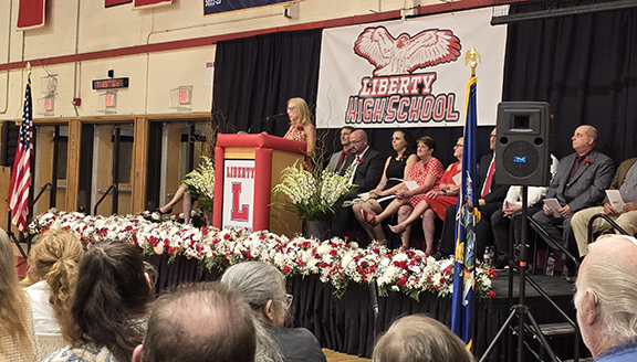 graduation31 A woman speaks at a podium with board members and administrators behind her