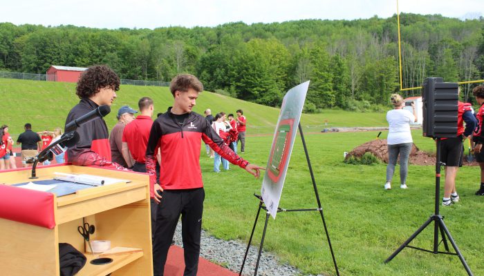 groundbreaking8 Two students look at the board featuring a drawing of the new field and track