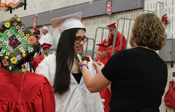 graduation26 An adult places a flower on a graduates robe.