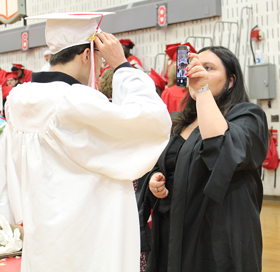graduation24 A student looks at at his cap in an adults phone.