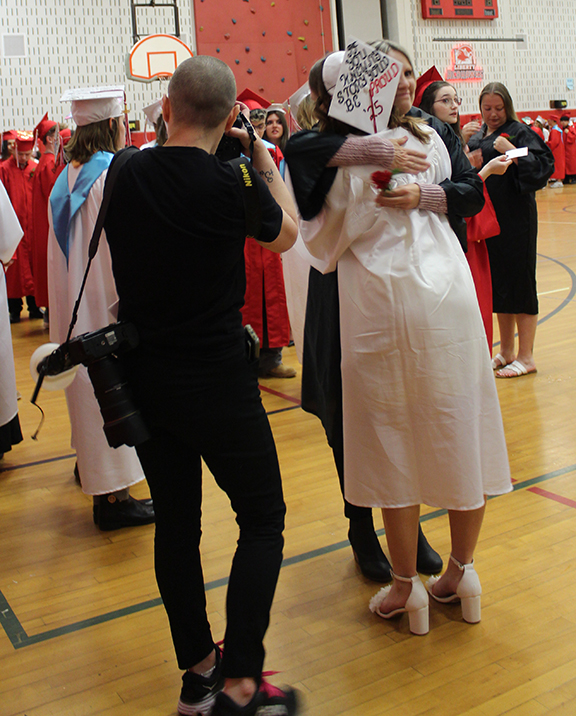 graduation21 A student hugs a n adult as a photographer takes a picture