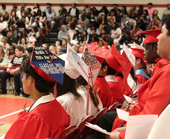 graduation14 Graduates sit with some with decorated caps