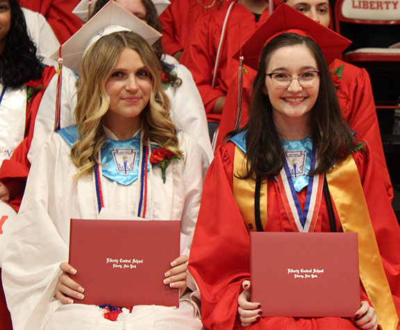 graduation13 Two students hold their diplomas and smile