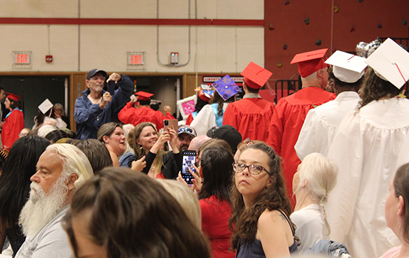 graduation12 An audience member takes a photo as graduates walk to the stage
