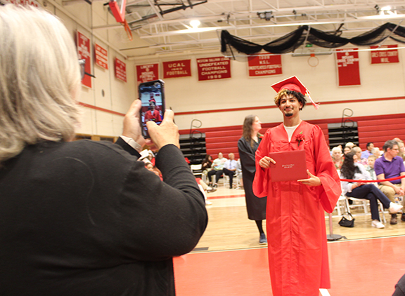 graduation6 An adult takes a picture of a student holding the diploma