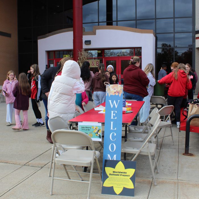 students and adults gather in front of the school