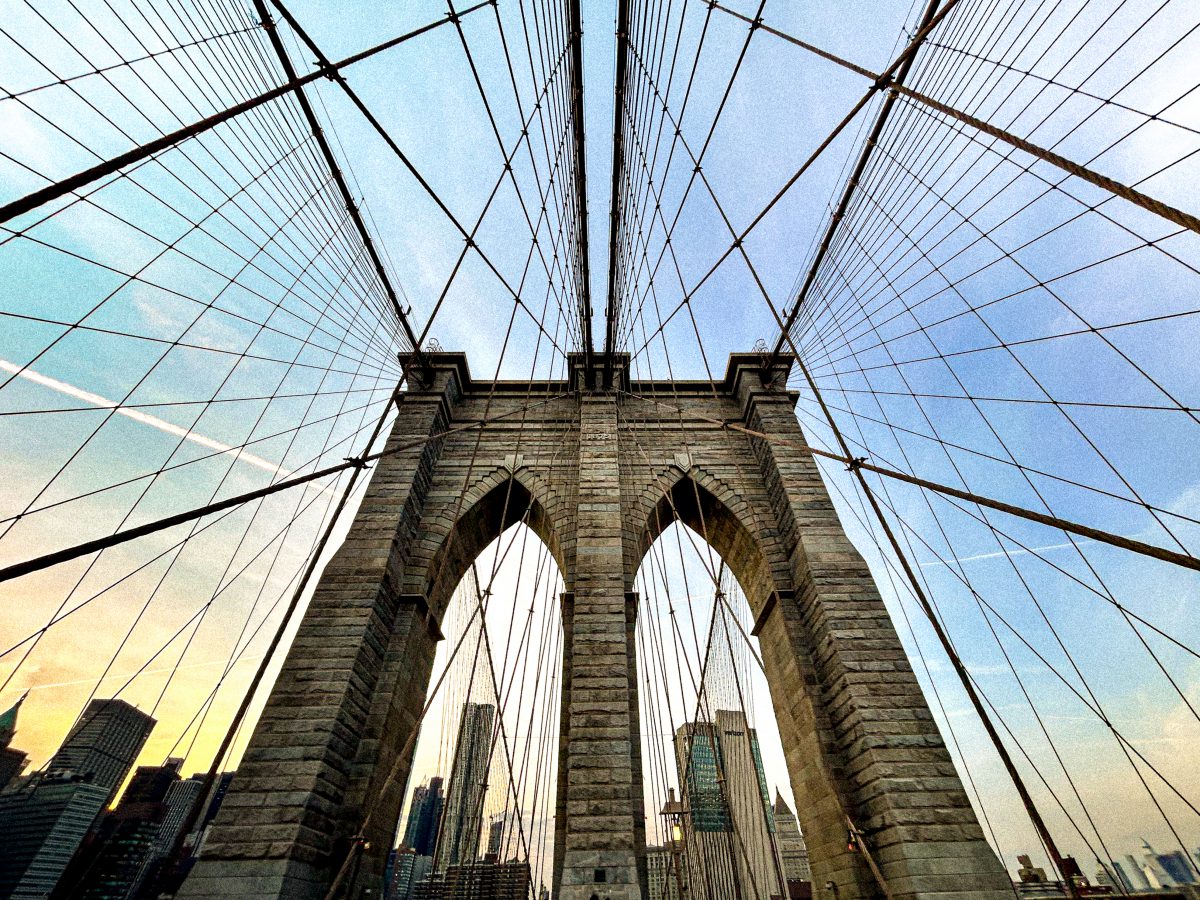 Look up from the deck of a suspension bridge with arched pillars