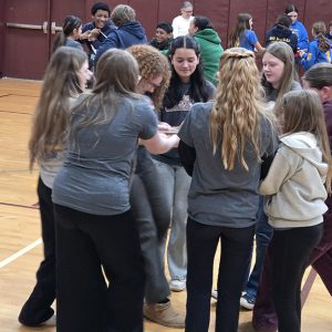 Students complete a team building exercise in a gym.