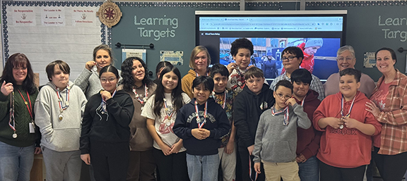 Students pose for a photo some wearing ribbons with a metal and pins on them.