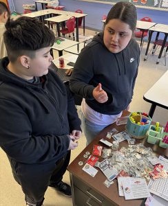 Two students look over Olympic pins on a table.