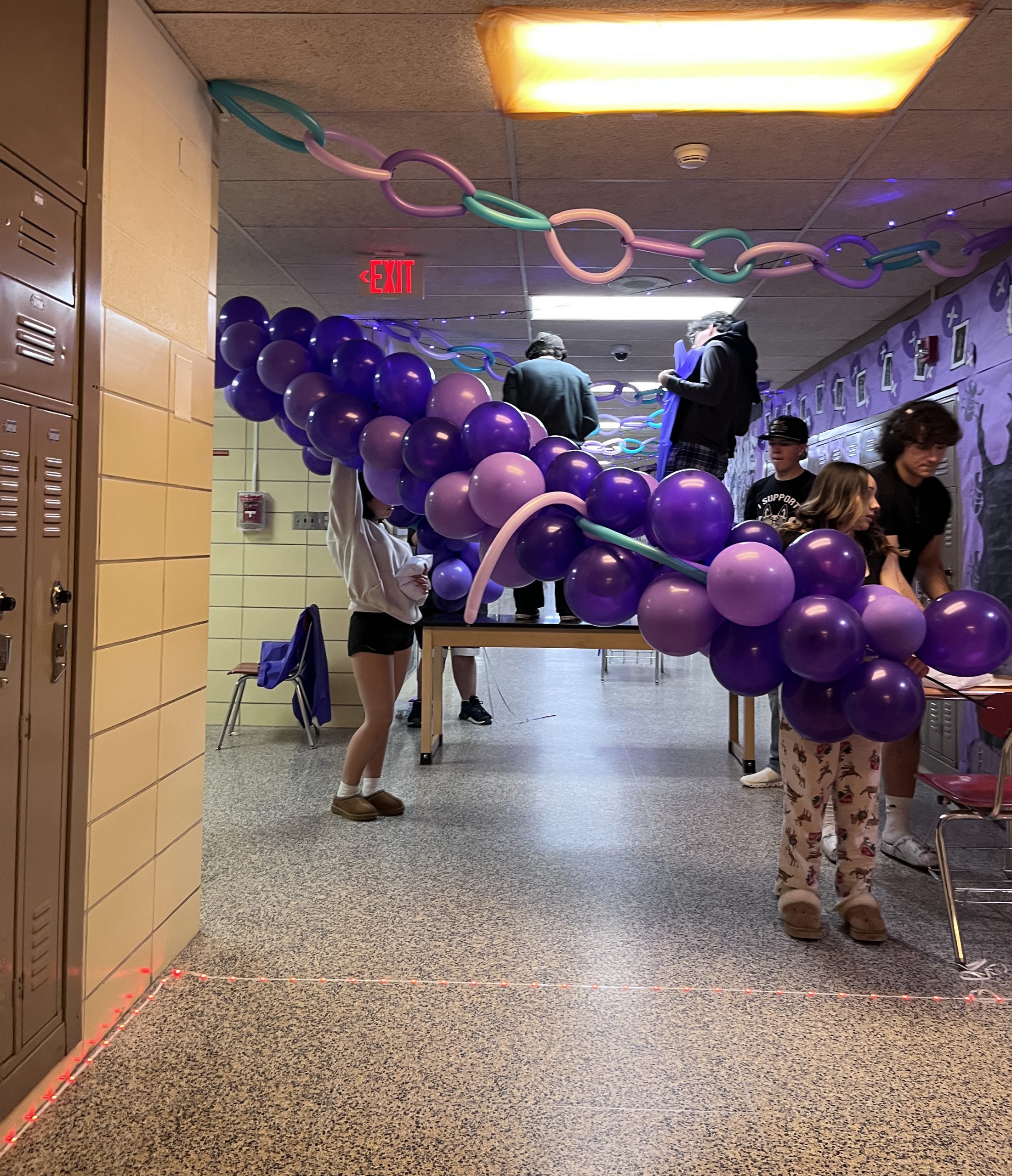 Students decorate a hallway with purple balloons