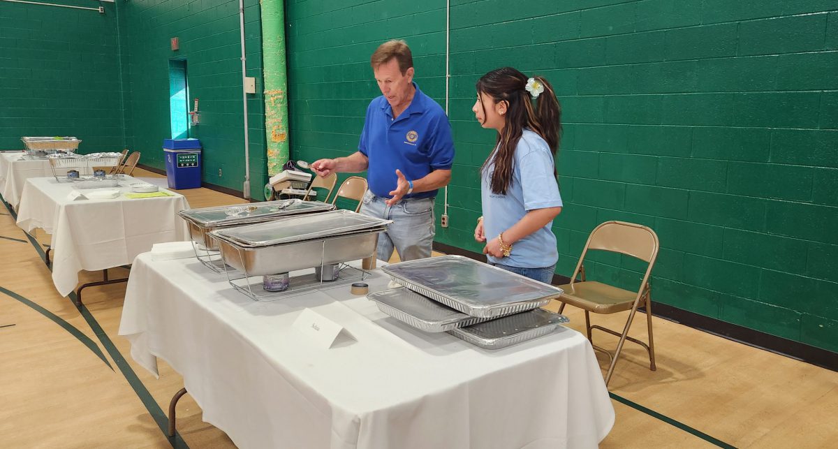 An adult and student prepare a table for serving food
