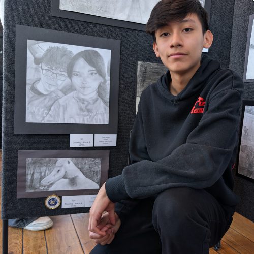 A student poses next to a black and white drawing