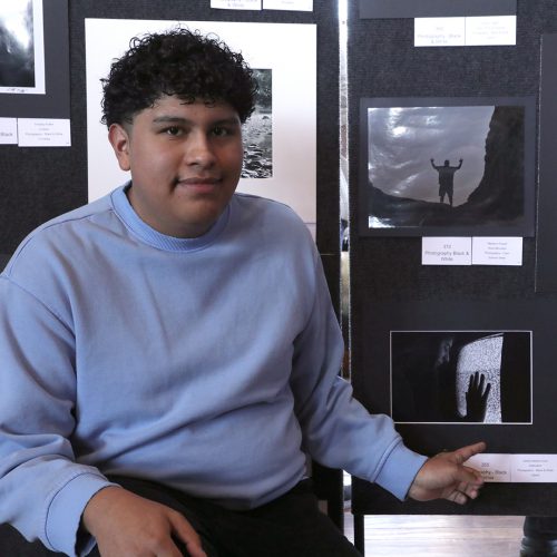 A student poses and points to his black and white photo