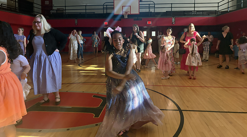 A student dances in the gym as others dance around her