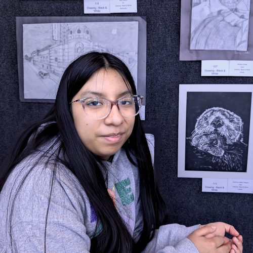 A student poses next to her black and white photo