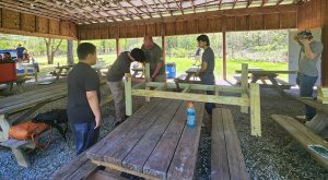 A man helps students build a bench
