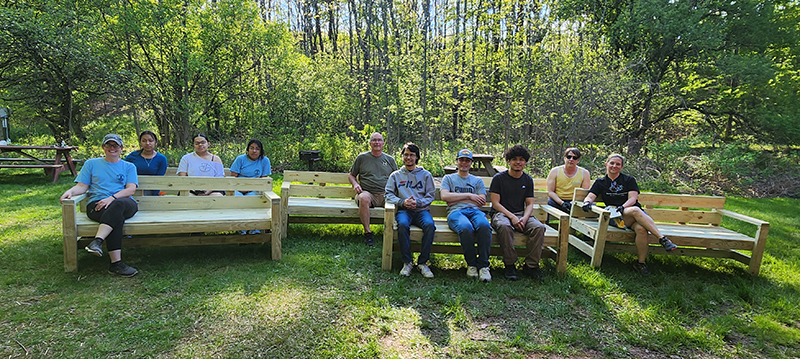 People sit on benches built by volunteers and the Interact Club