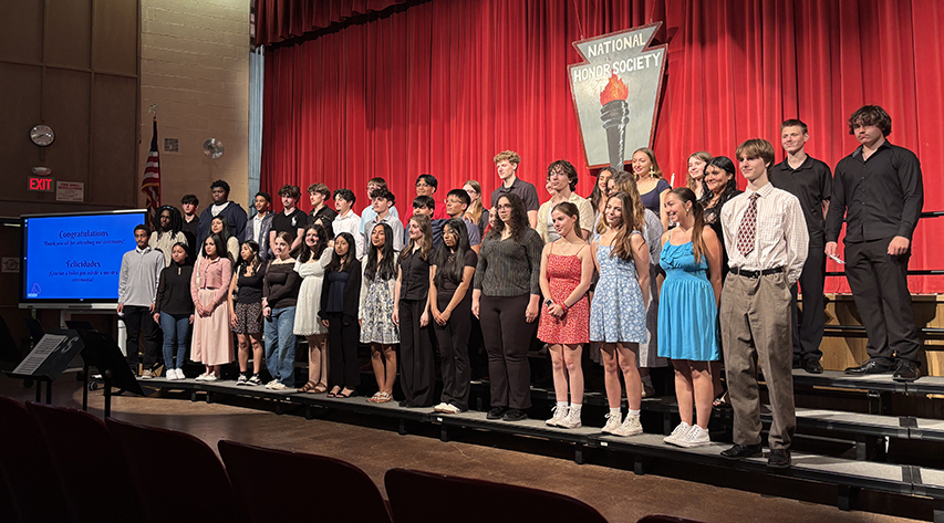Students pose for a photo standing on risers