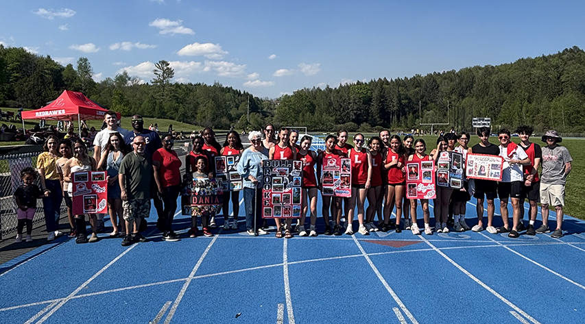 Track and field athletes and their families pose for a photo on a track.