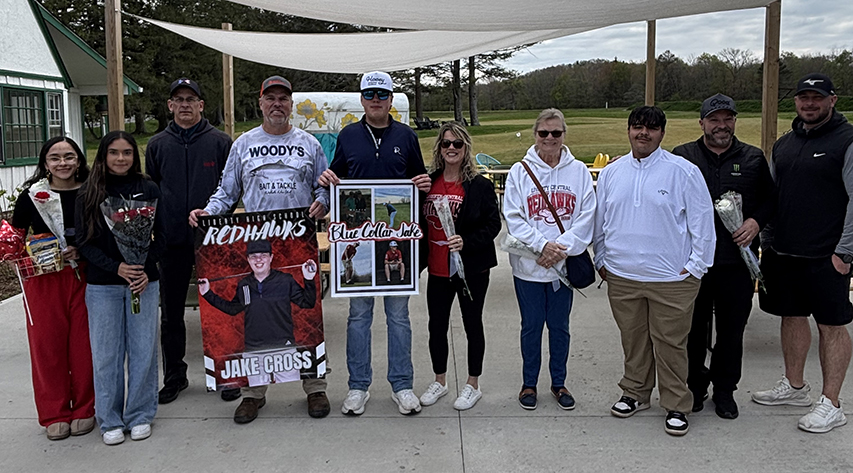 Golfers and their families pose for a photo on a track.