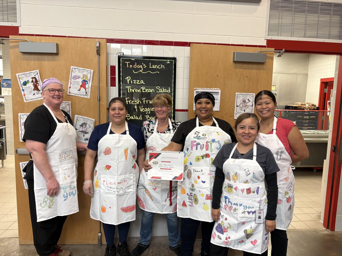 Cafeteria works pose with their school luncg hero day aprons.